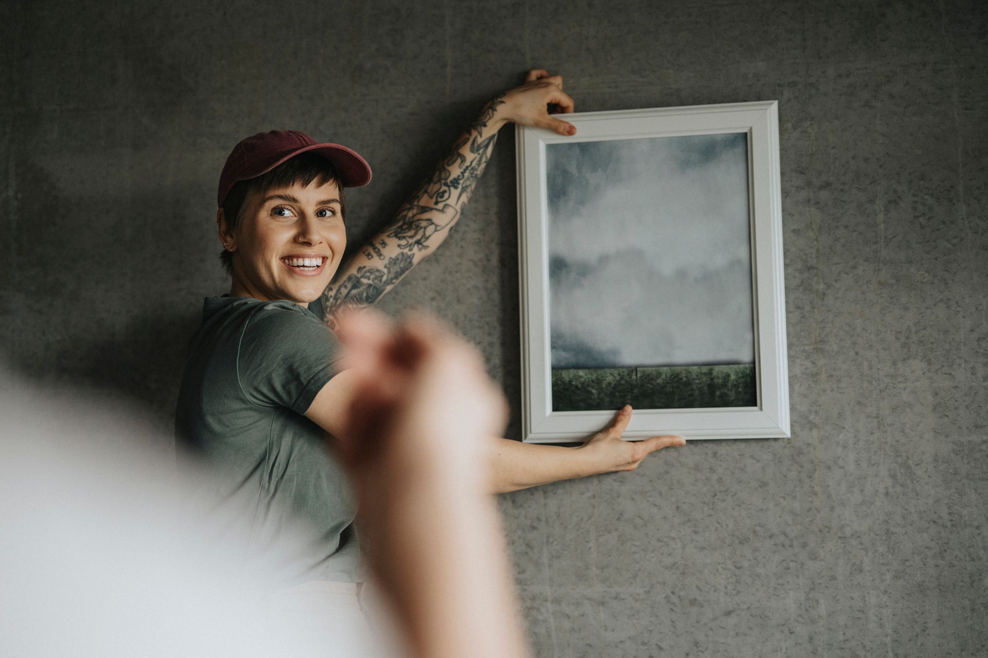 Woman taking guidance while hanging frame on wall at home.