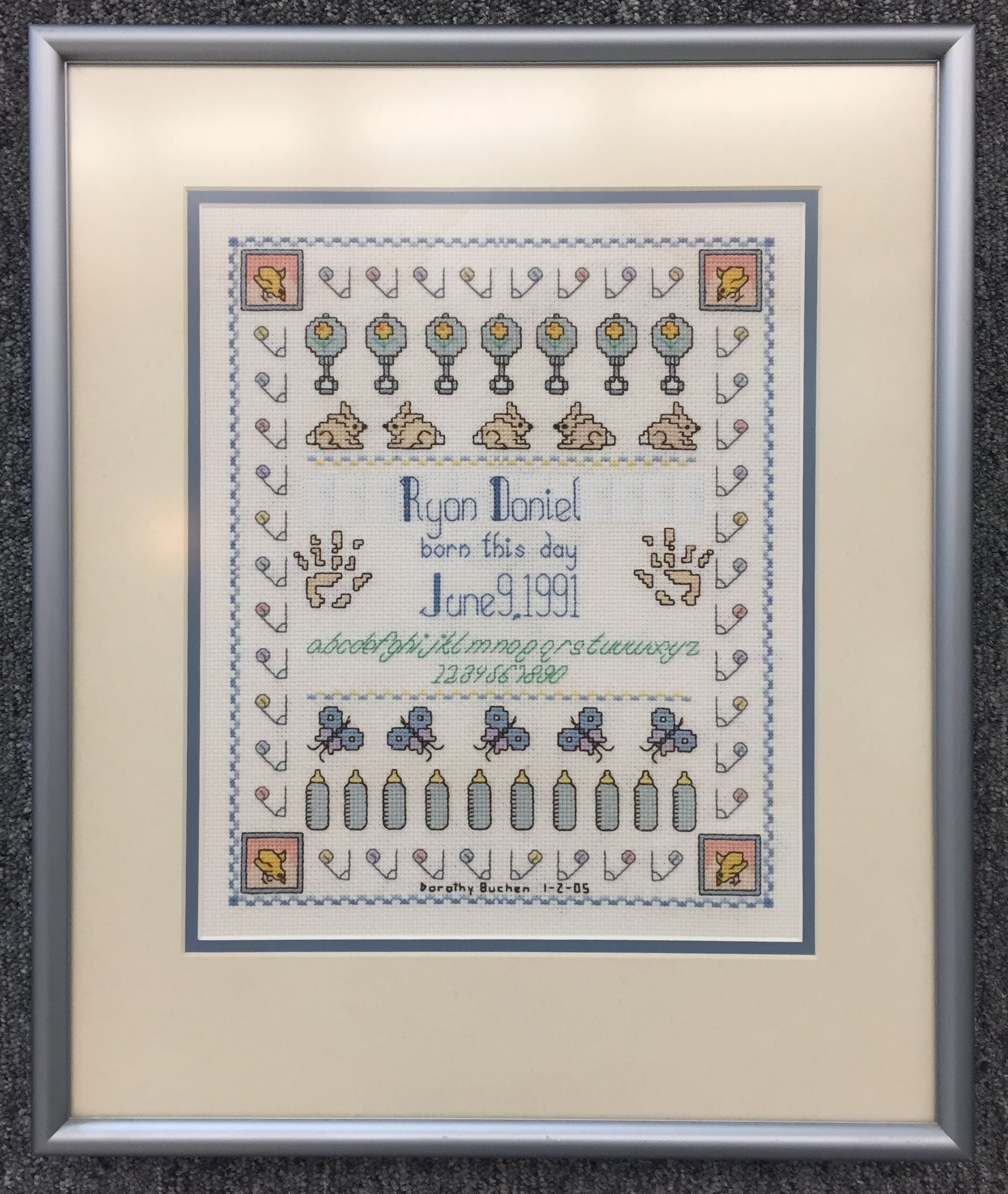 Framed cross-stitch art; pale blue and beige design; name 