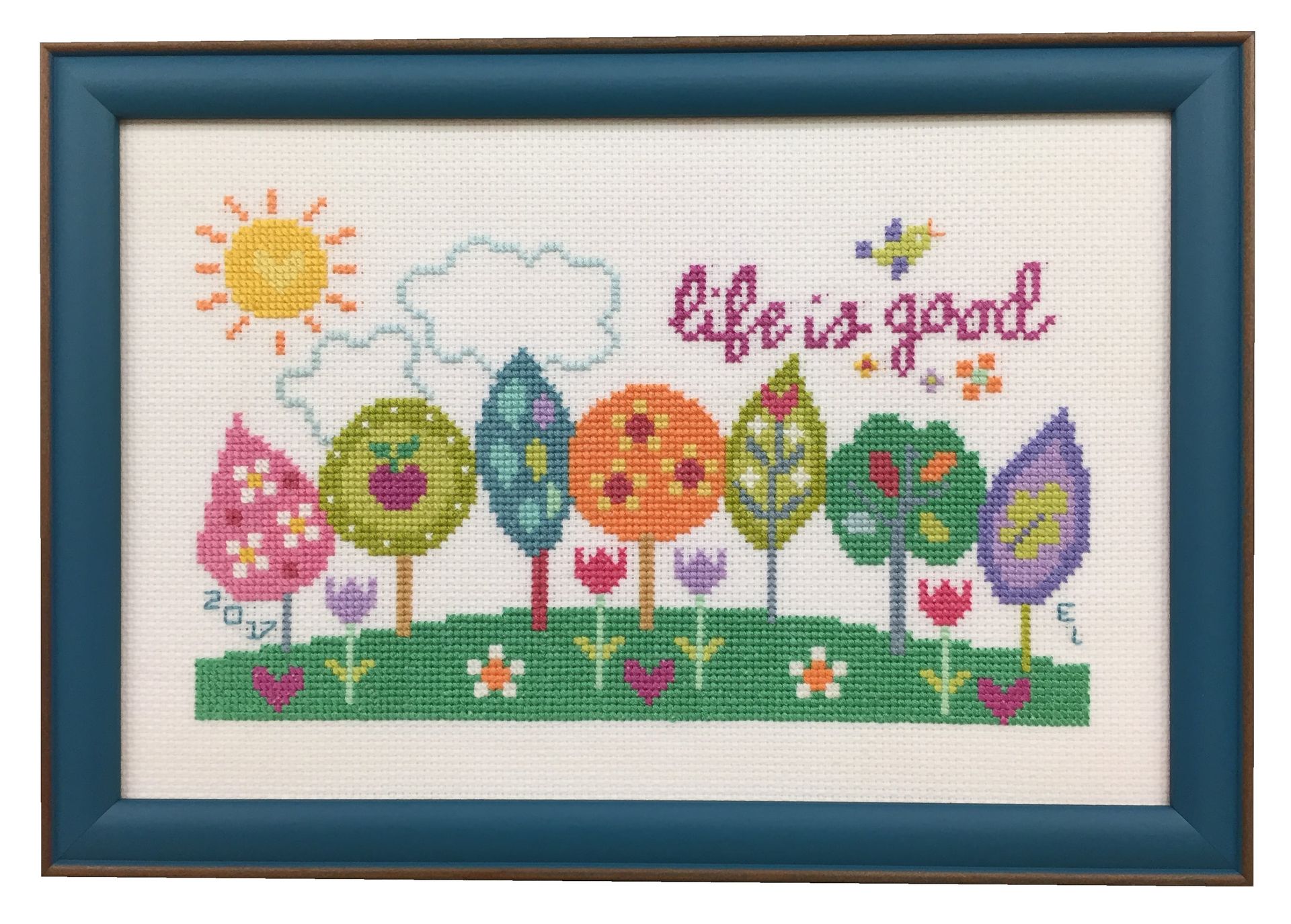 Cross-stitch of colorful trees, a sun, and 