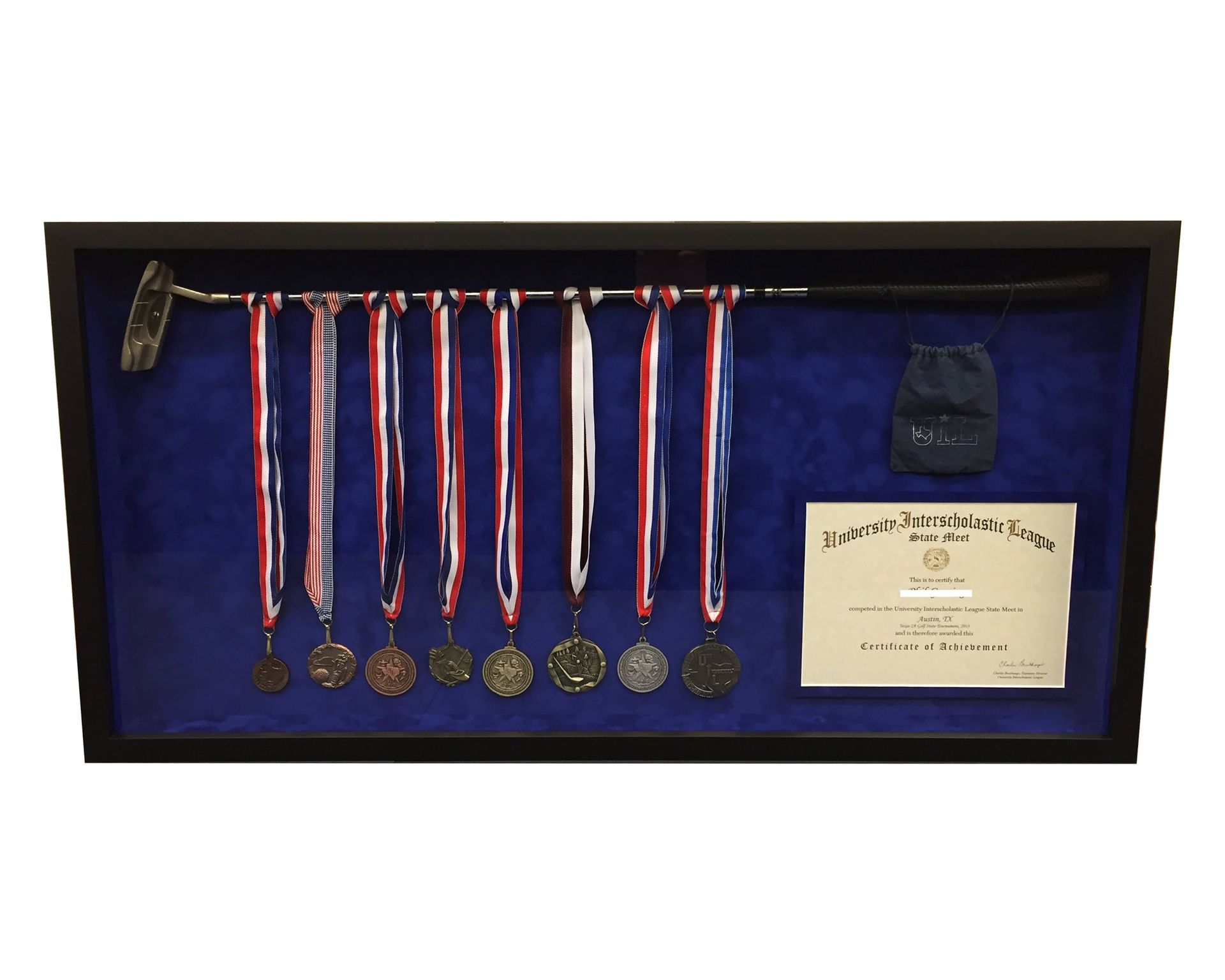 Display case with golf club, medals with red, white, and blue ribbons, and a certificate.