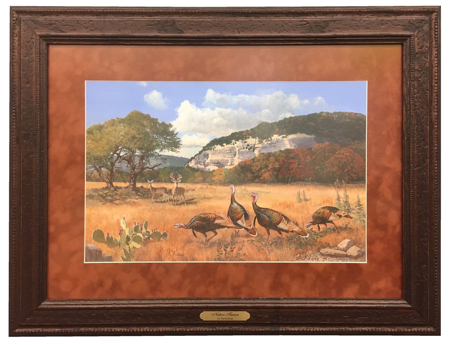A framed landscape with turkeys in a field, mountain backdrop, and cloudy sky.