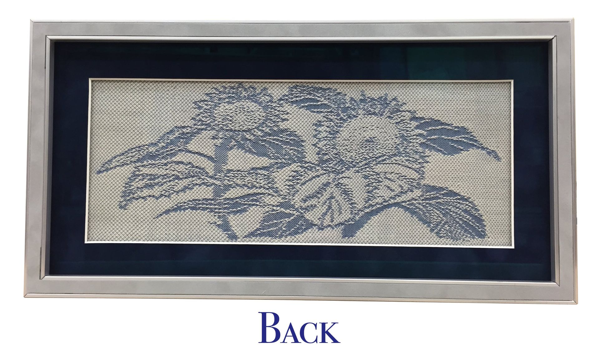 Framed artwork featuring a textured silver floral design on a dark blue and green background.