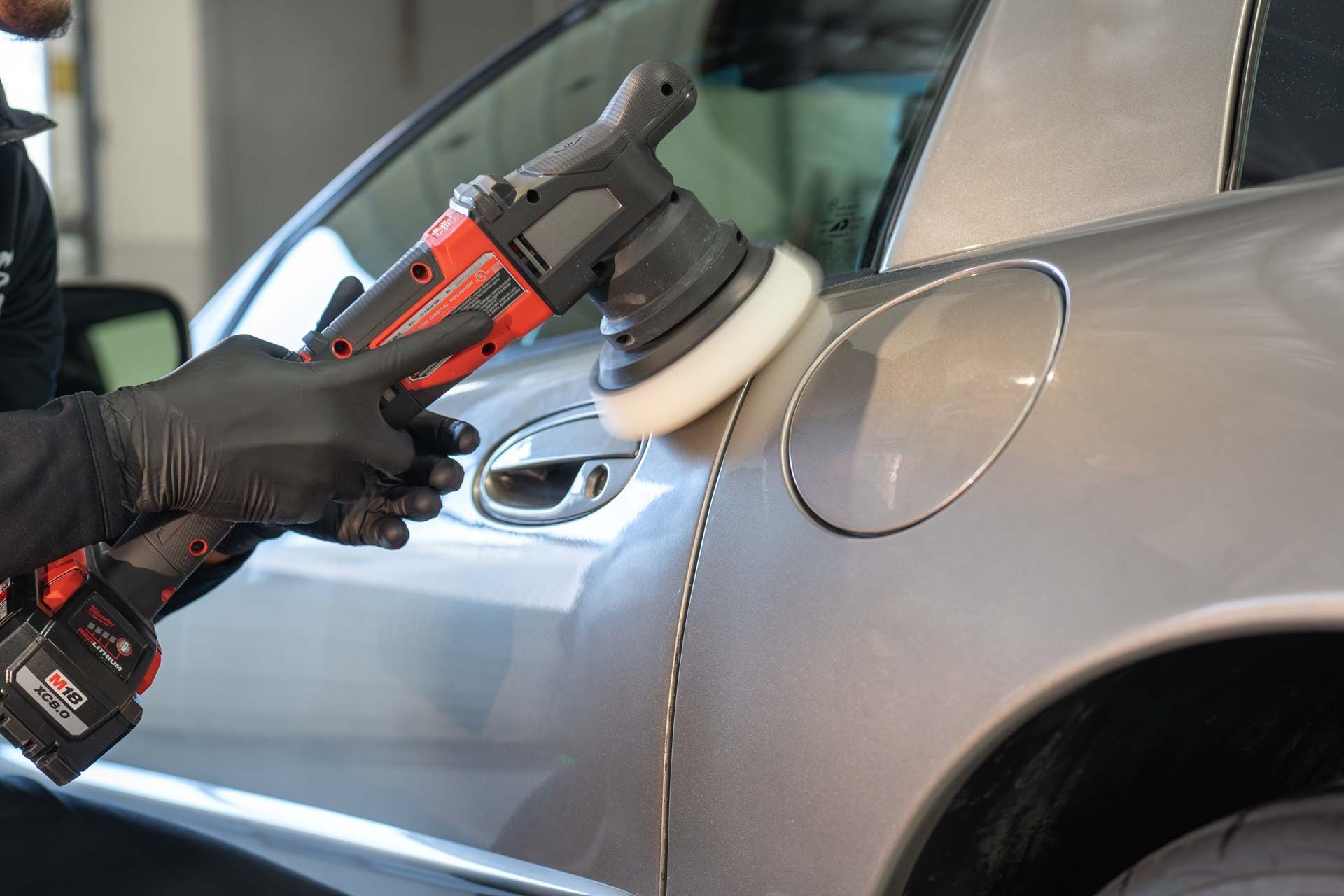 A person is polishing a car with a machine.