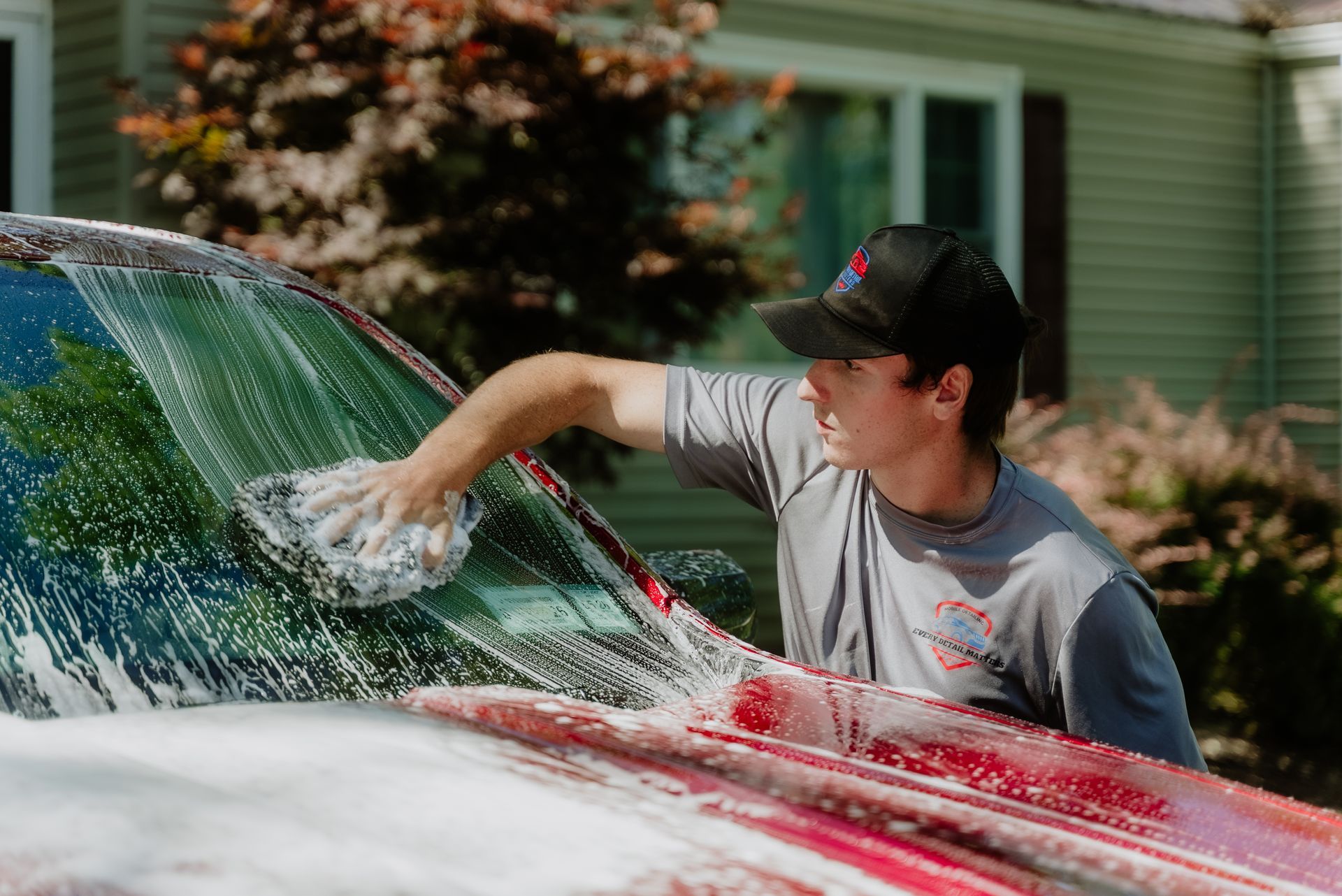 A woman is washing a car with a sponge.
