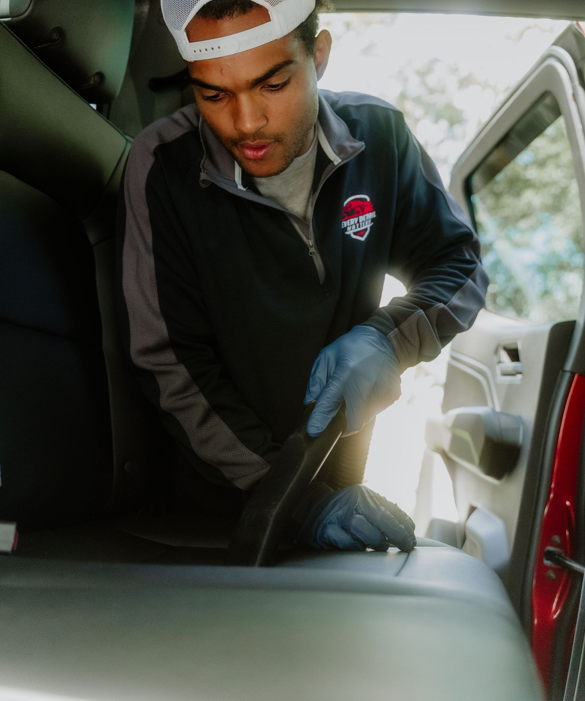 A man is cleaning the interior of a car with a cloth.
