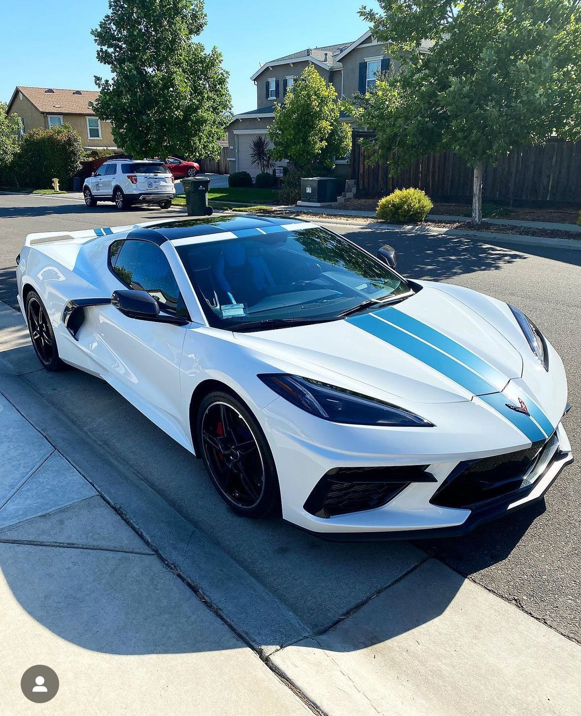 A white sports car is parked on the side of the road.