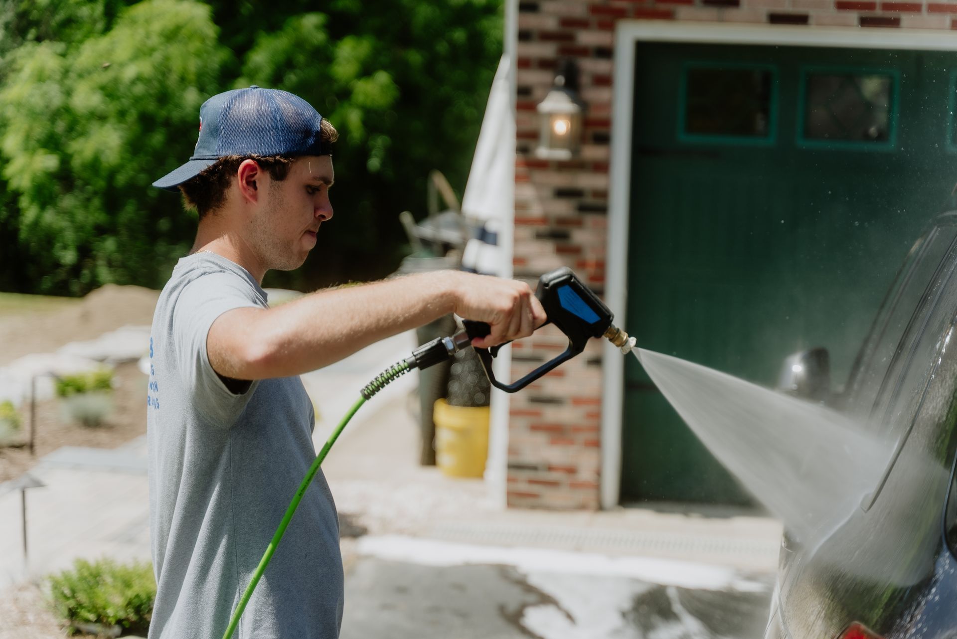 A man is washing a black car with a spray bottle.