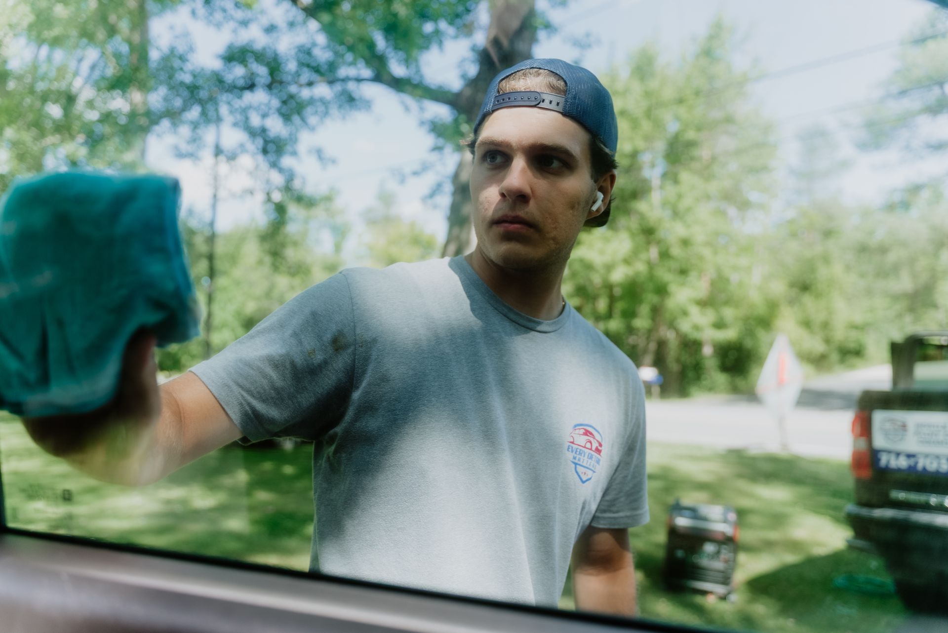 A man is polishing the hood of a car with a machine.