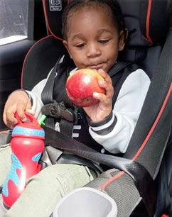 Teacher giving a high-five to a student in a classroom setting. Other children are seated at desks.