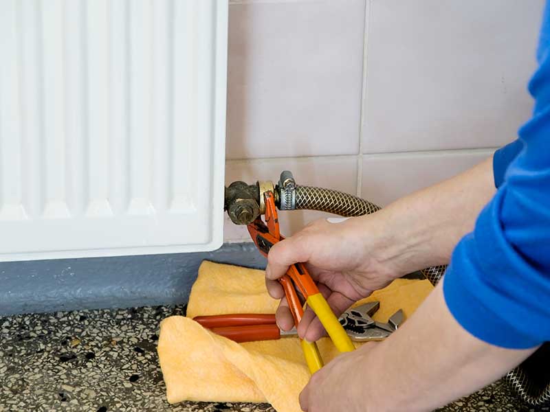 tecnico mentre interviene su un termosifone domestico