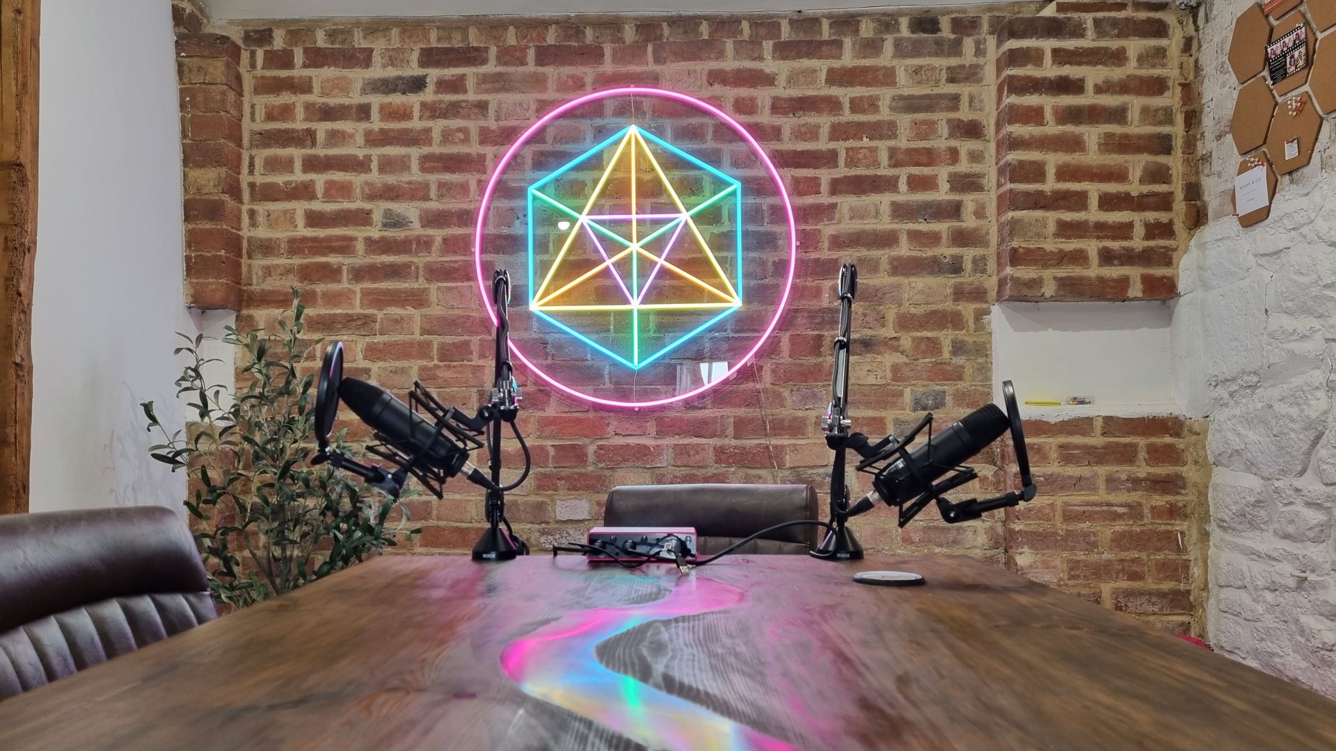 A conference room with two microphones and a neon sign on the wall.