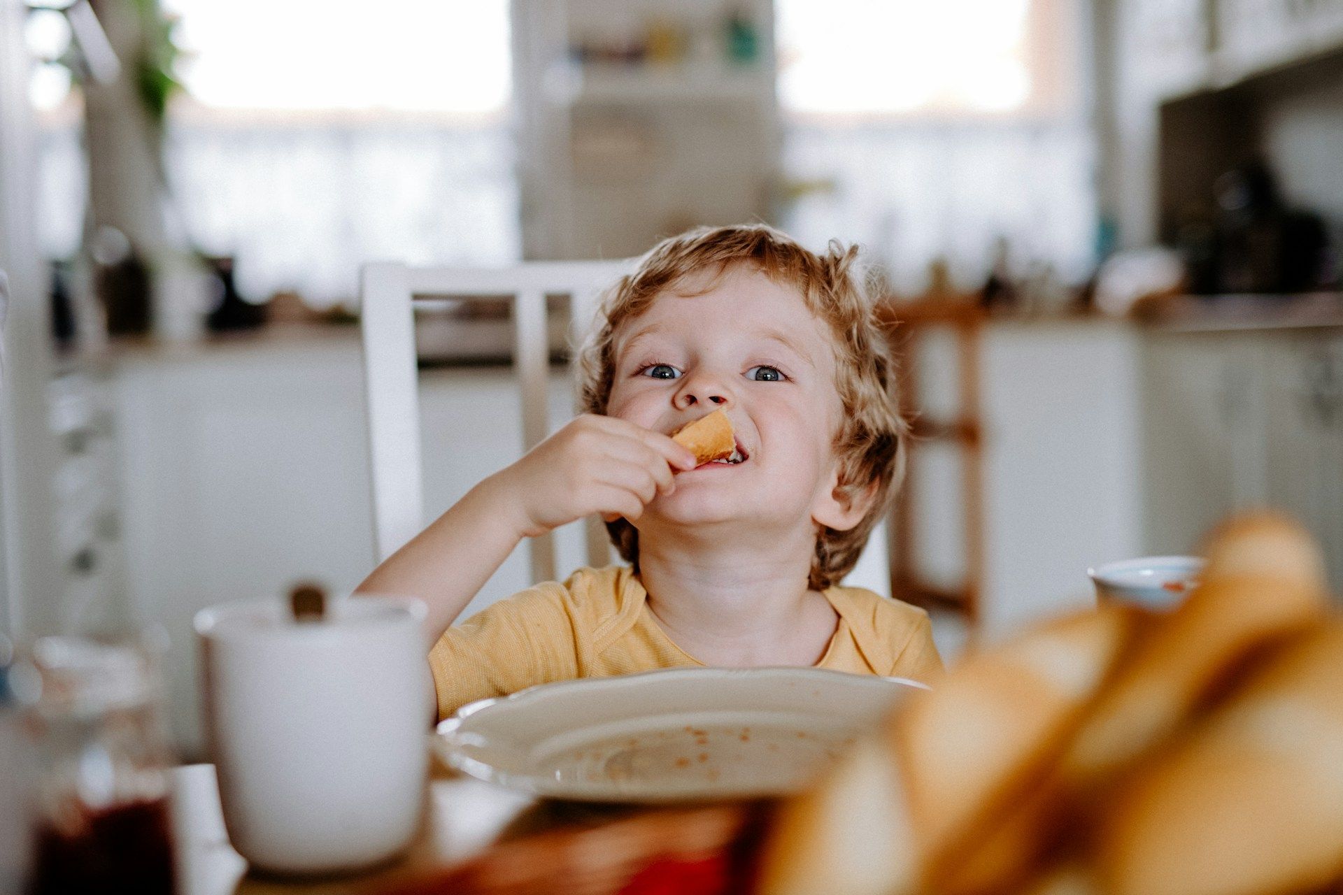 A young boy is sitting at a table eating food.