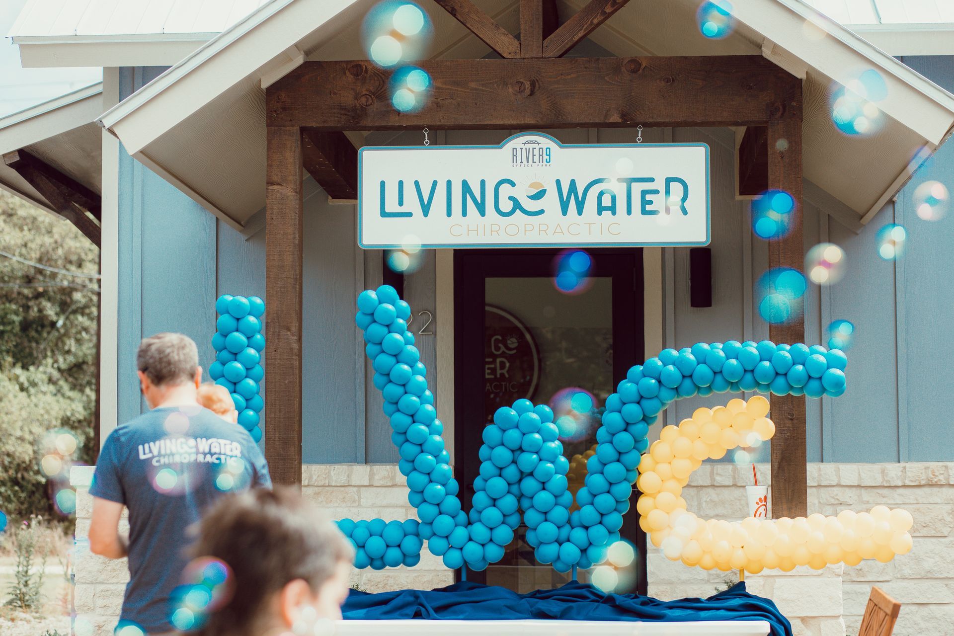 Blue and yellow balloon letters spelling LWC stand in front of a building with a 