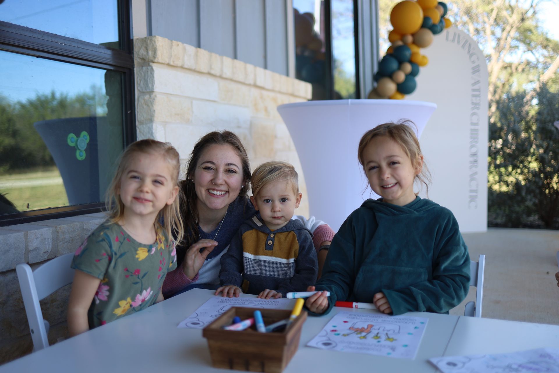 Woman and three children smiling at a Living Water Chiropractic party outdoors