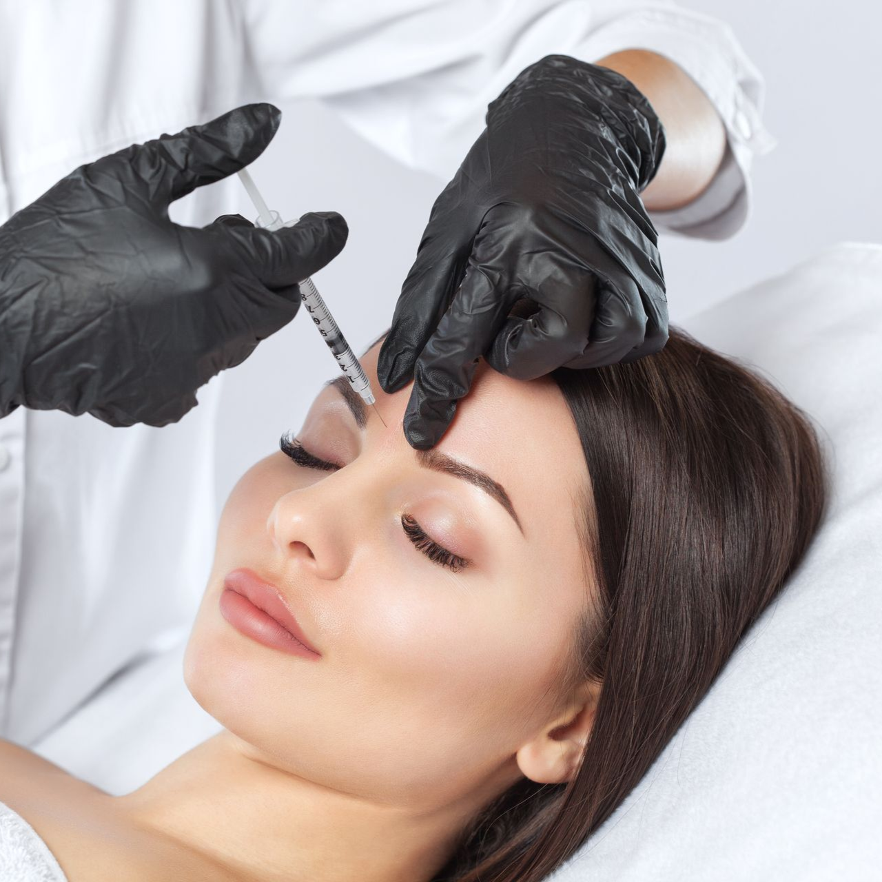 Gloved hands administering eyebrow treatment to a woman lying back in a spa setting