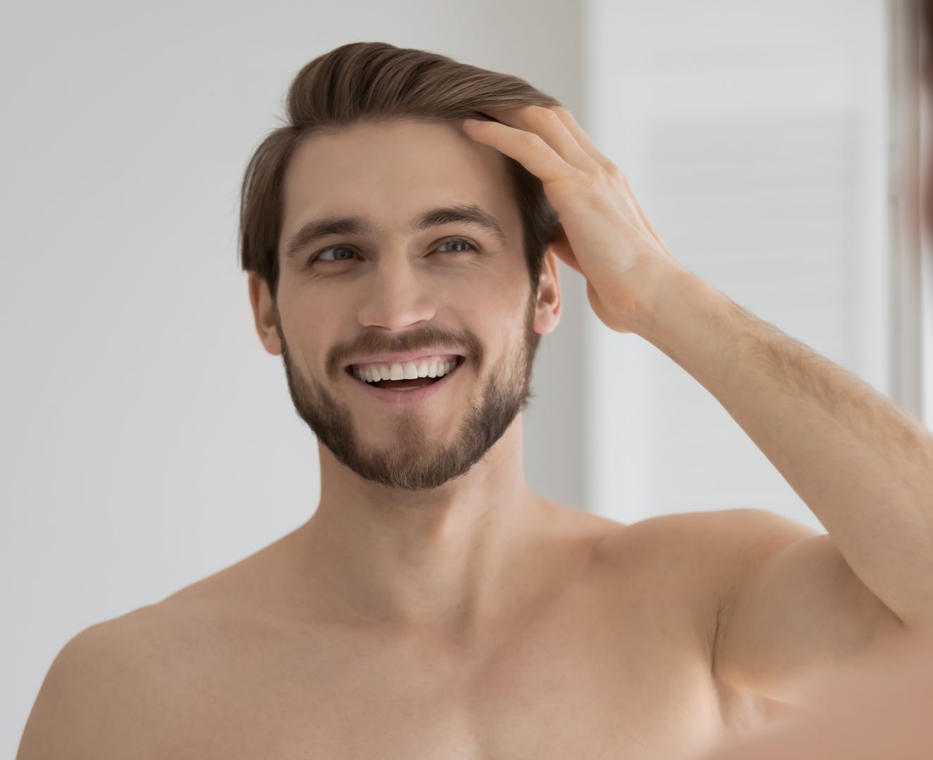 a man smiling and touching his hair
