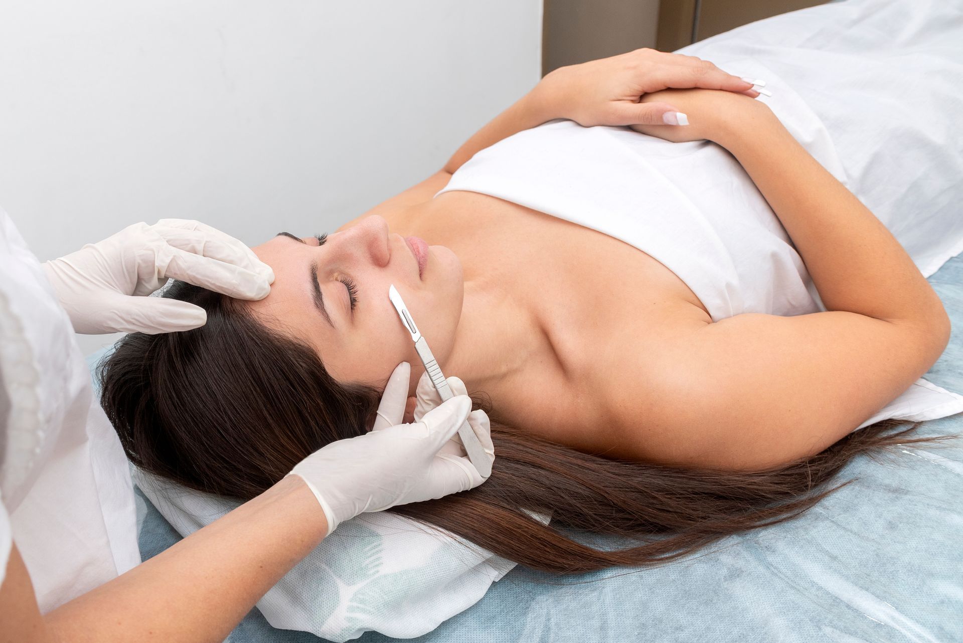 A provider in gloves performs a cosmetic facial injection on a person lying on a treatment table.