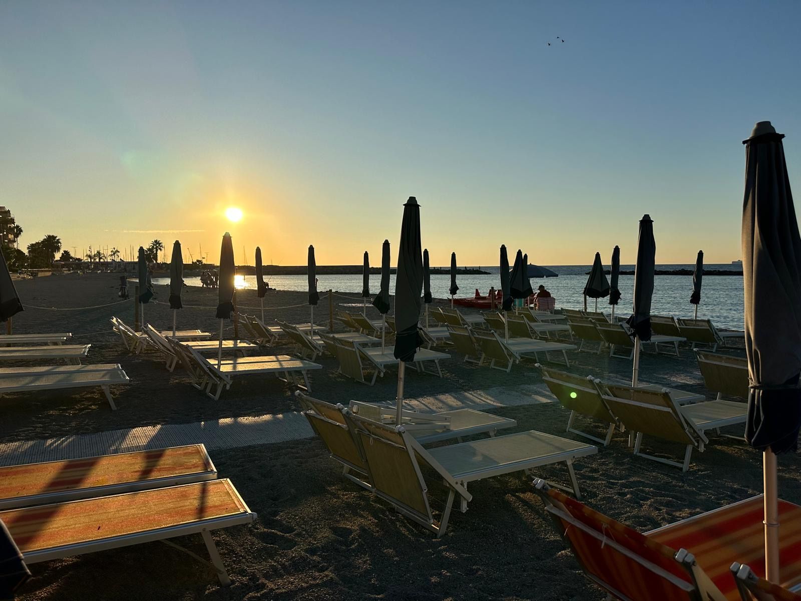 Una spiaggia con ombrelloni e sedie a sdraio in una giornata di sole