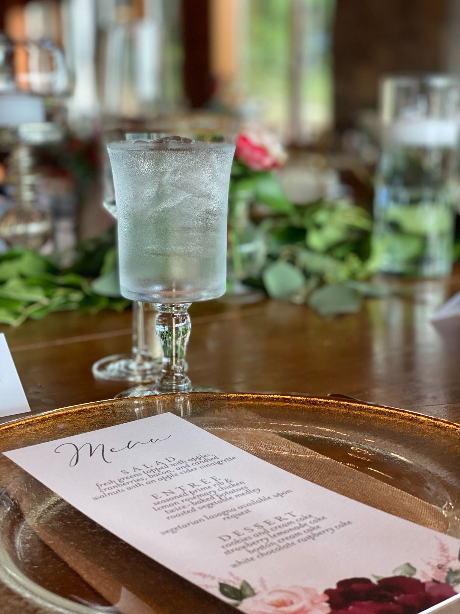 A frosted cocktail glass on a tray beside a floral menu in a softly lit restaurant setting