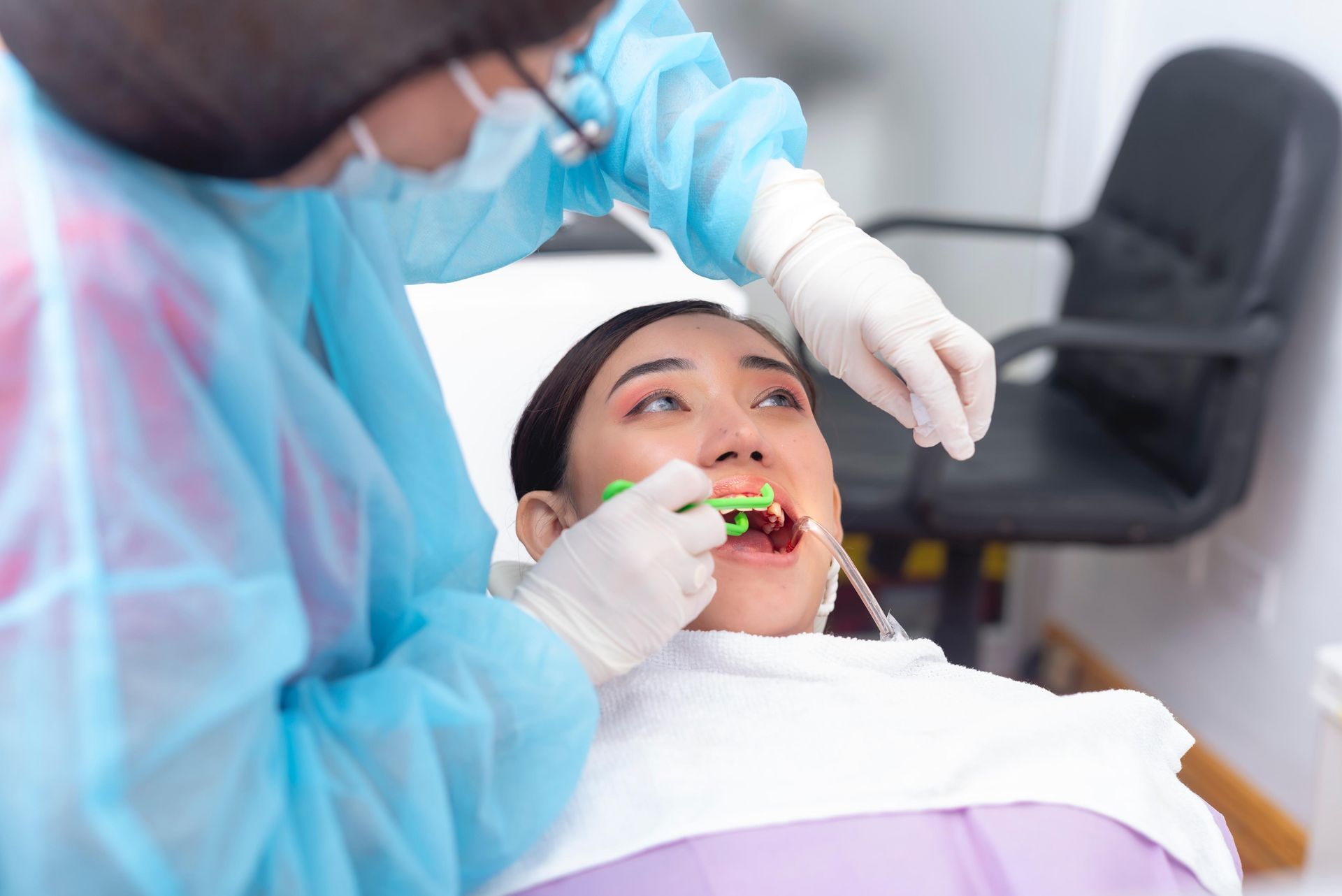 A dentist uses a dental floss holder to clean in-between the teeth of a female patient. 