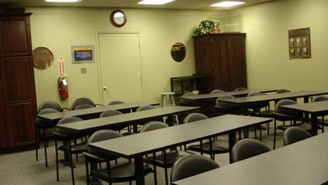 a classroom with tables and chairs and a clock on the wall .