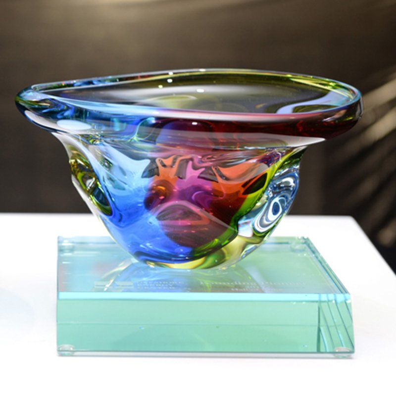 A colorful glass bowl is sitting on a glass base