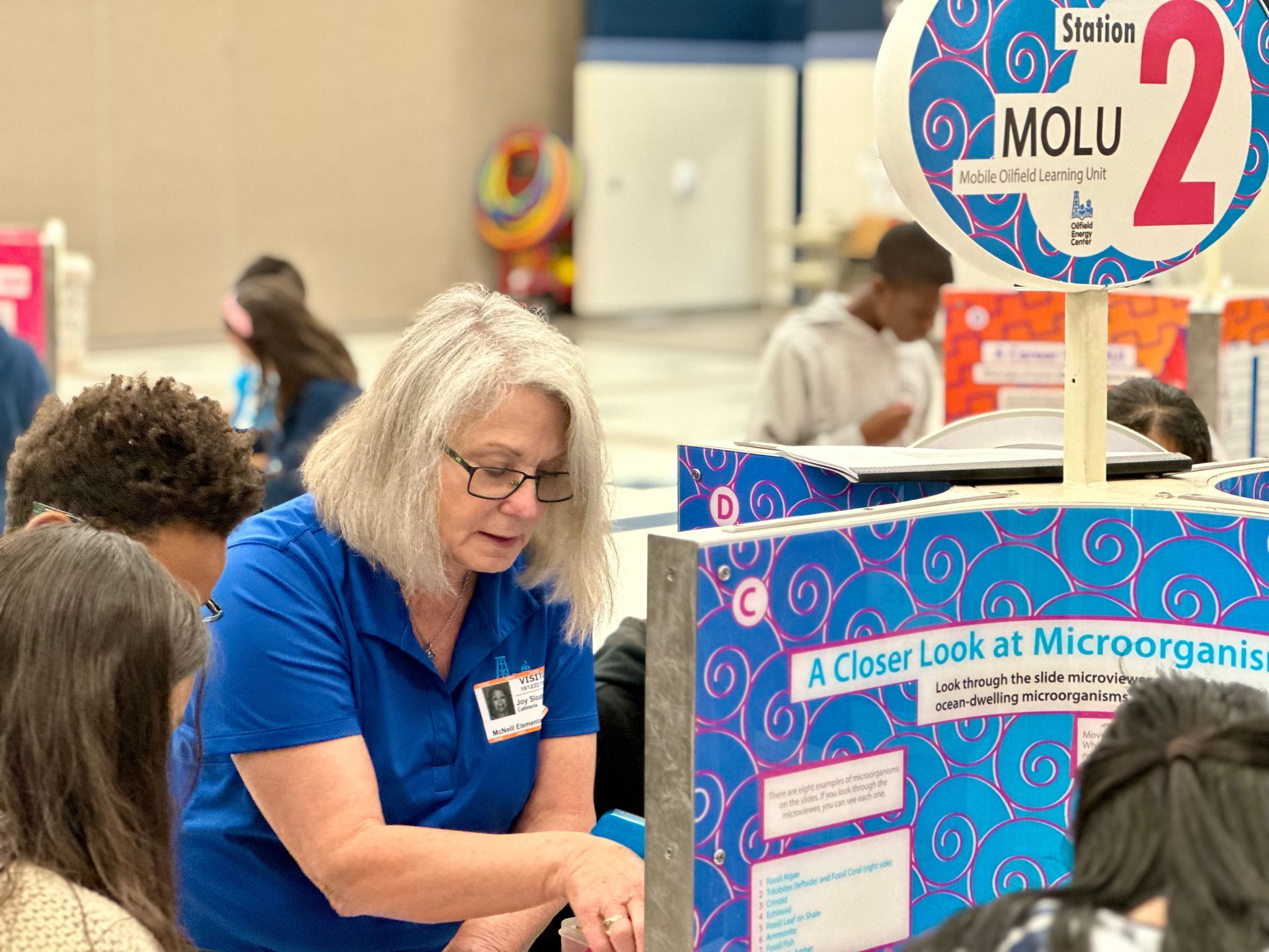 A woman is talking to a group of students at a science fair.