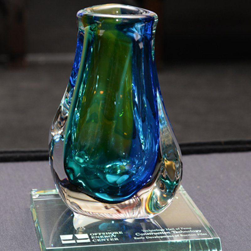 A blue and green glass vase sits on a glass pedestal