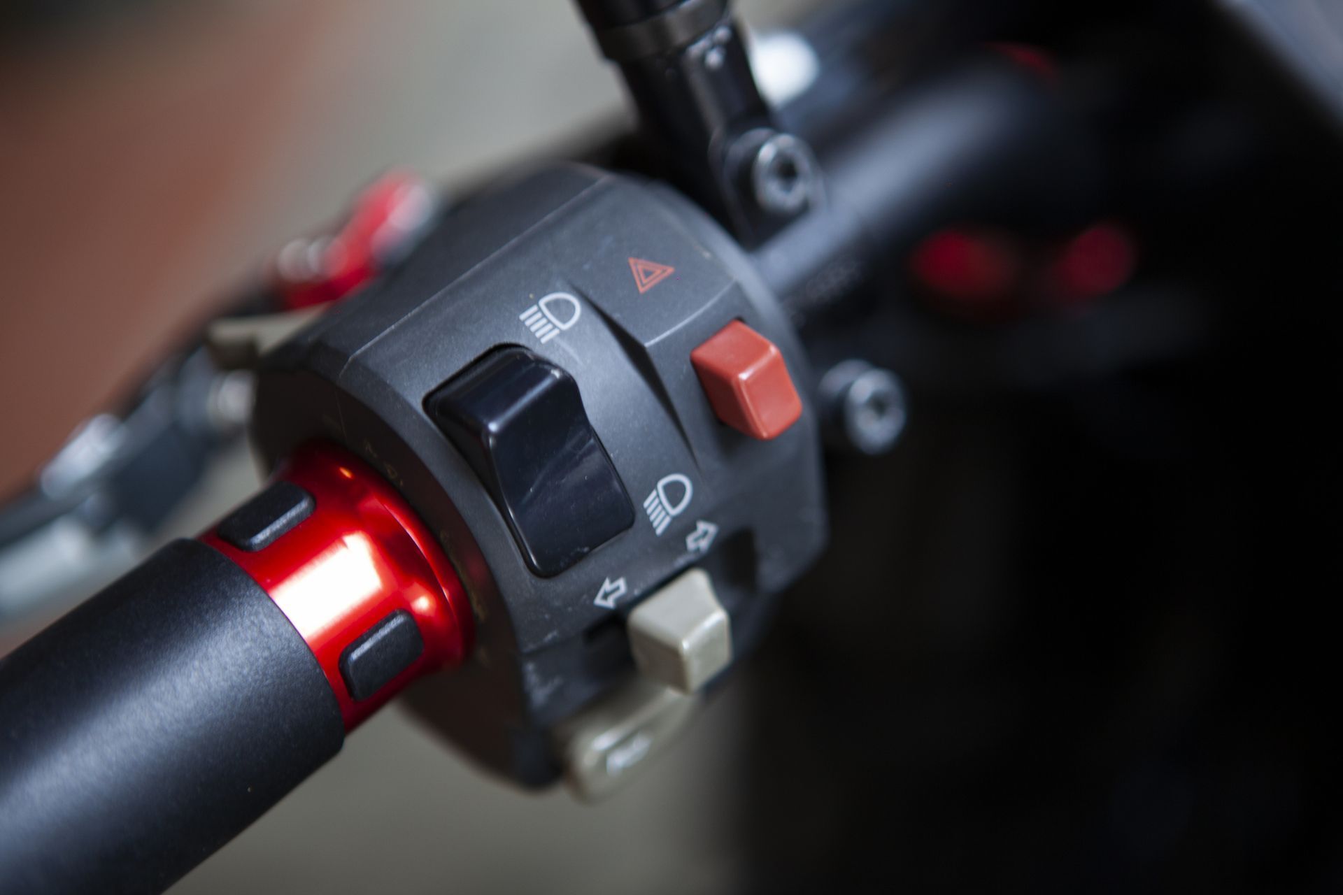 Motorcycle handlebar controls: Black switch for headlight, red hazard button, and turn signal controls.