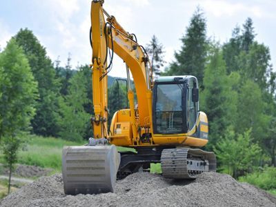 A yellow excavator is sitting on top of a pile of gravel.