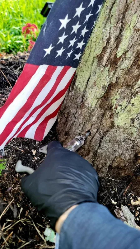 A person wearing black gloves is standing next to an american flag.