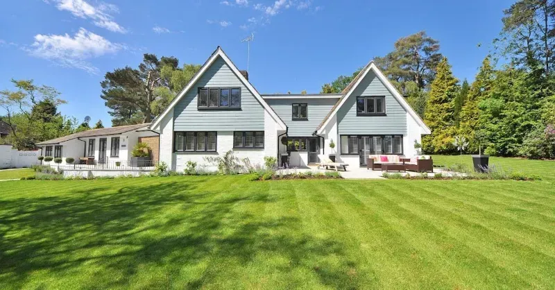 A house with a lush green lawn and a tree in front of it