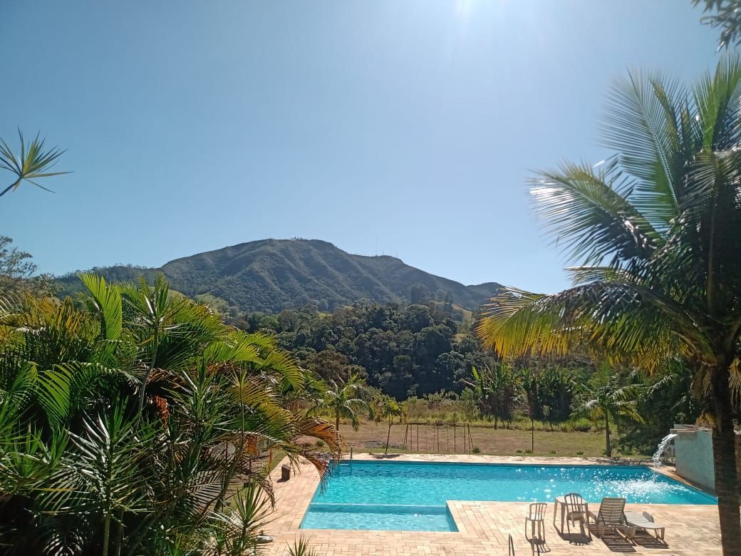 Piscina com vista para a montanha, rodeada por folhagem tropical sob um céu azul brilhante.