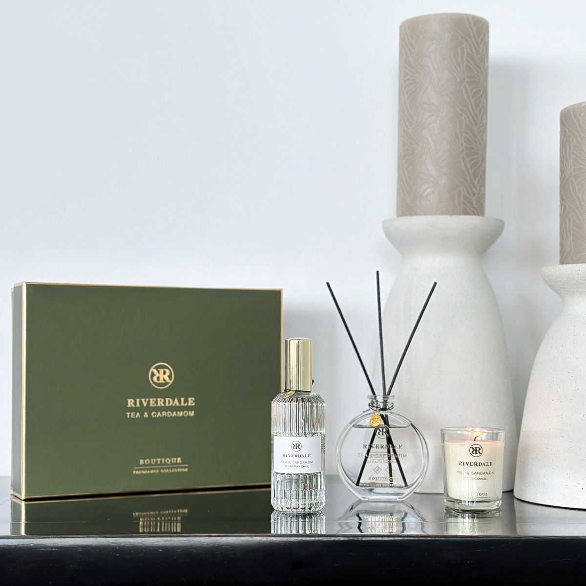 Luxe geurstokjesset met geurkaars, bestaande uit een zwart-gouden doos en een transparante fles op een witte achtergrond.