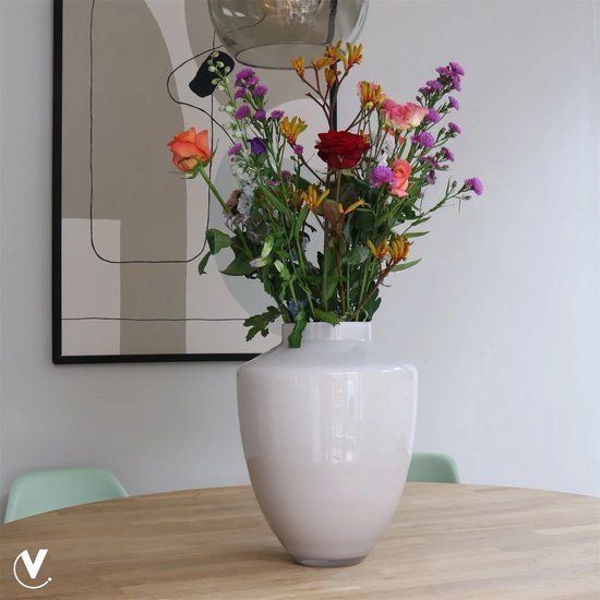 Een vaas met roze bloemen, twee spiraalvormige kaarsen in zwarte houders en een dienblad op een houten tafel.