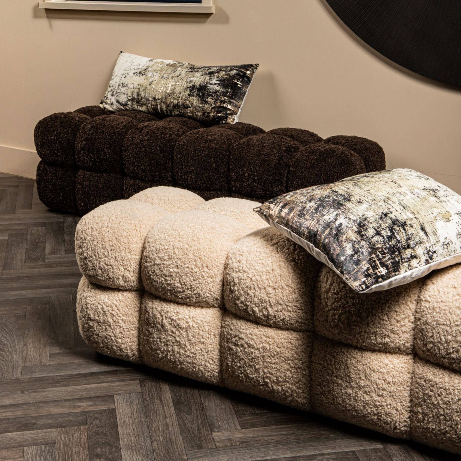 Bruine, afgeronde, gestructureerde bank, waarschijnlijk van bouclé, tegen een witte achtergrond.