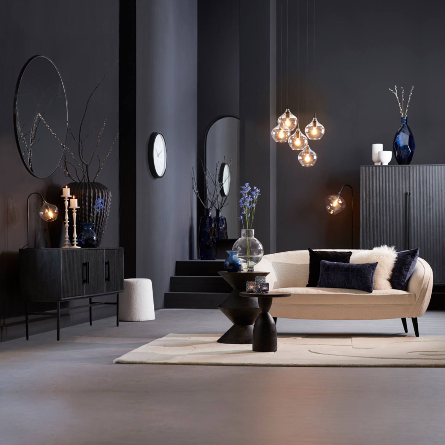 Donkere kamer met crèmekleurige bank, zwarte meubels en decoratieve accenten. en verlichting