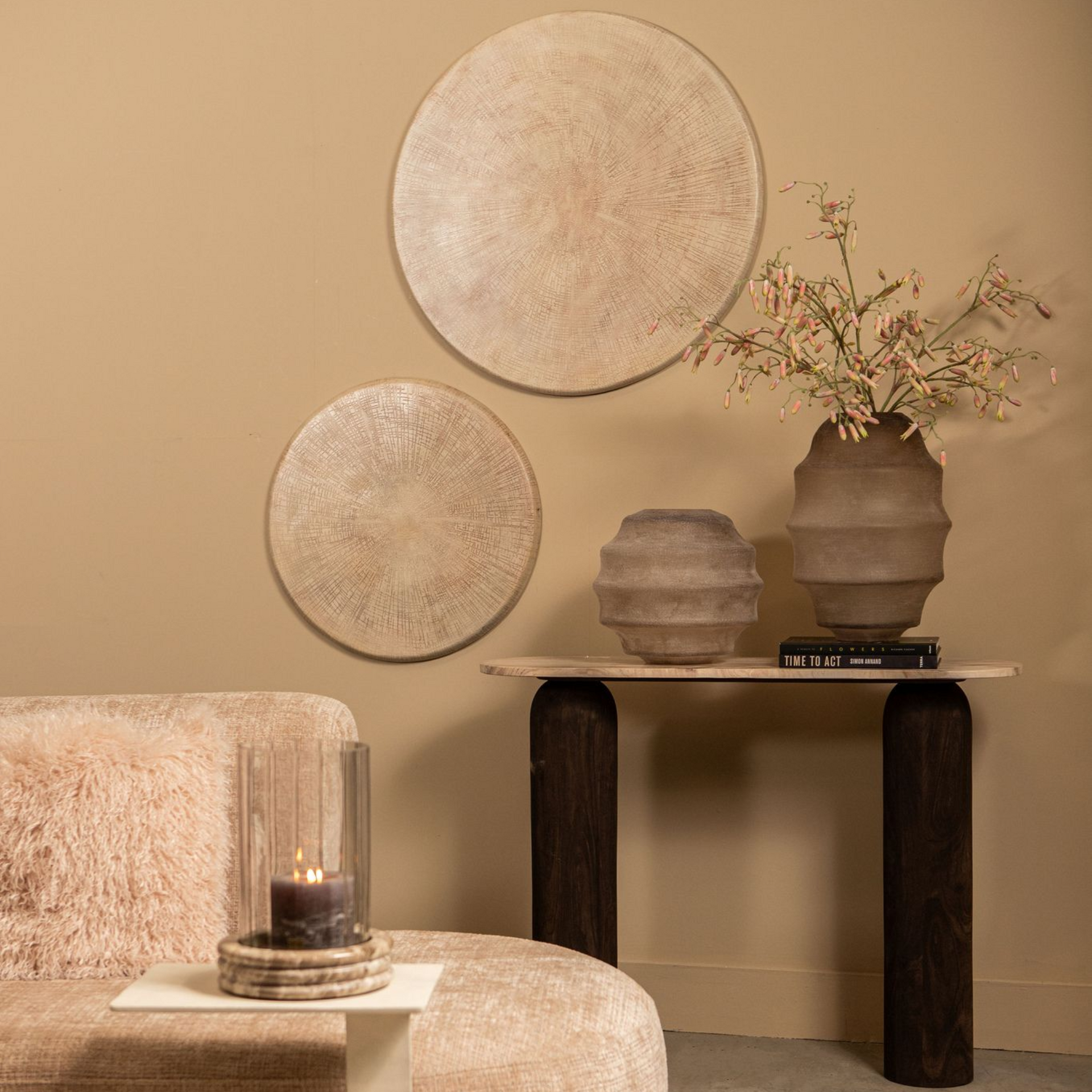 Woonkamer met beige muren, decoratie zoals ronde wanddecoratie, vazen en een bank.