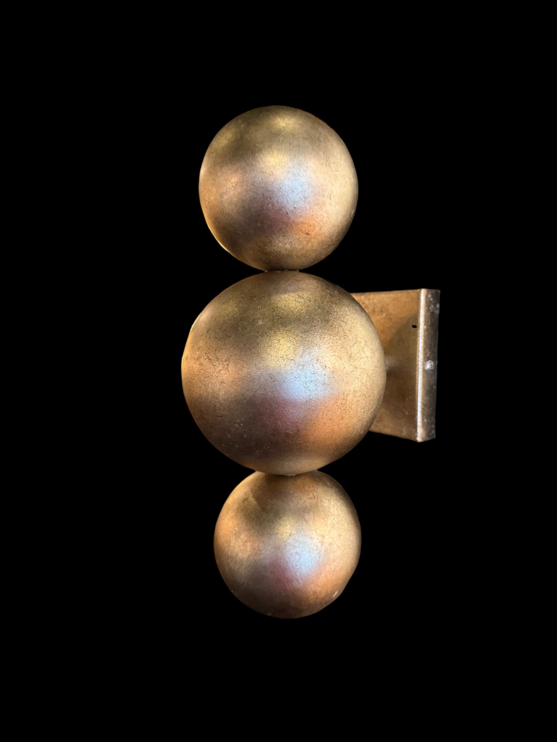 Goudkleurige wandlamp met drie verticaal gestapelde bollen.