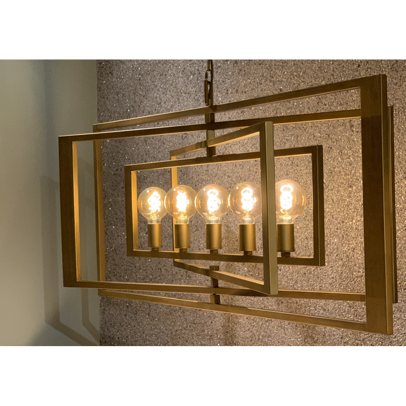 Geometrische gouden lamp met vijf lampen, hangend voor een muur met structuur.