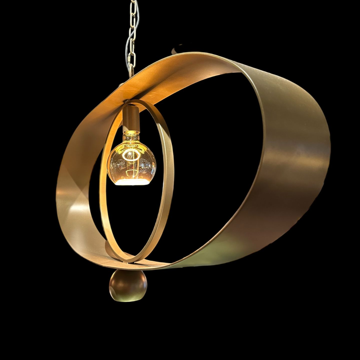 Een moderne, goudkleurige hanglamp met in elkaar overlappende metalen ringen en een enkele brandende lamp.