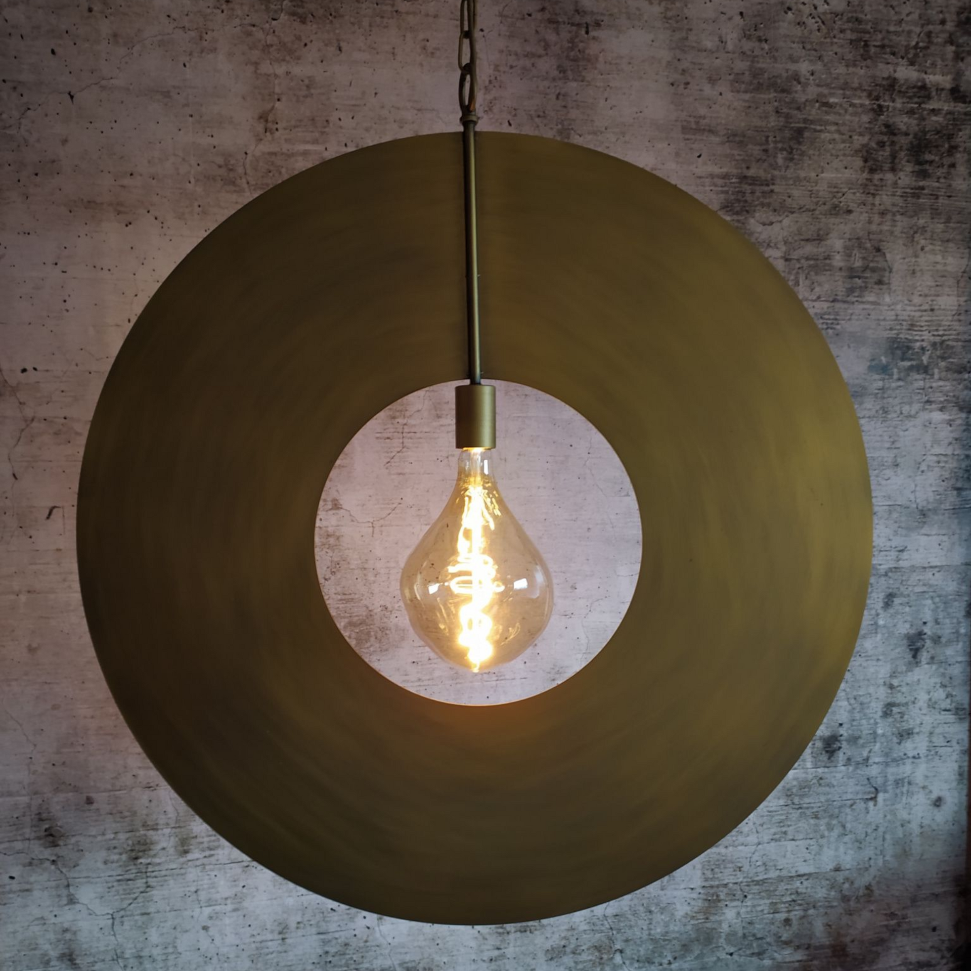 Messingkleurige ronde hanglamp met een zichtbare druppelvormige gloeilamp in een witte ronde uitsparing.