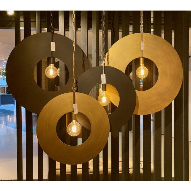 Vier ronde hanglampen met zichtbare lampen hangen voor een zwarte wand met lamellen.