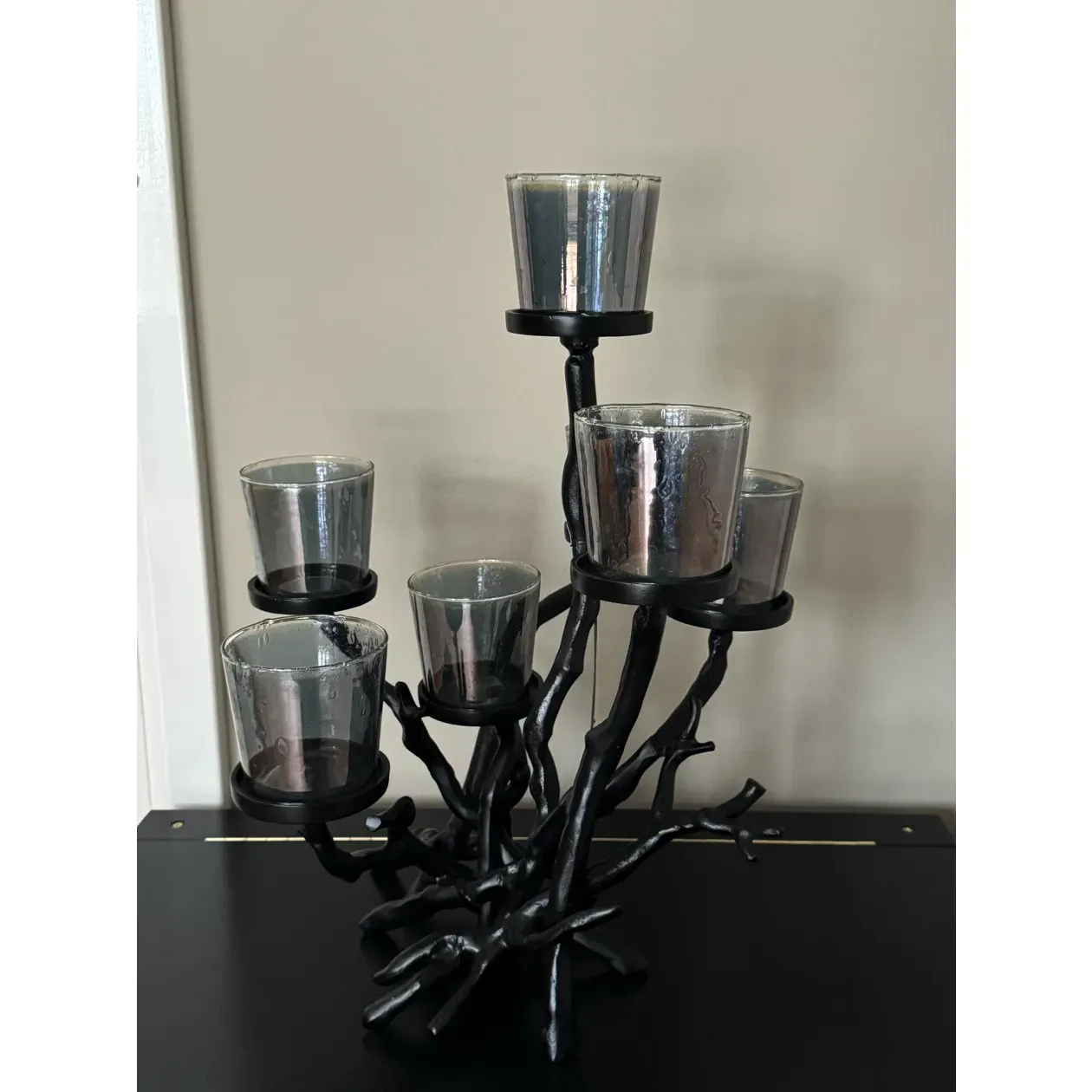 Zwarte kandelaar met zeven brandende kaarsen op een donkere ondergrond, die een zacht licht verspreidt.