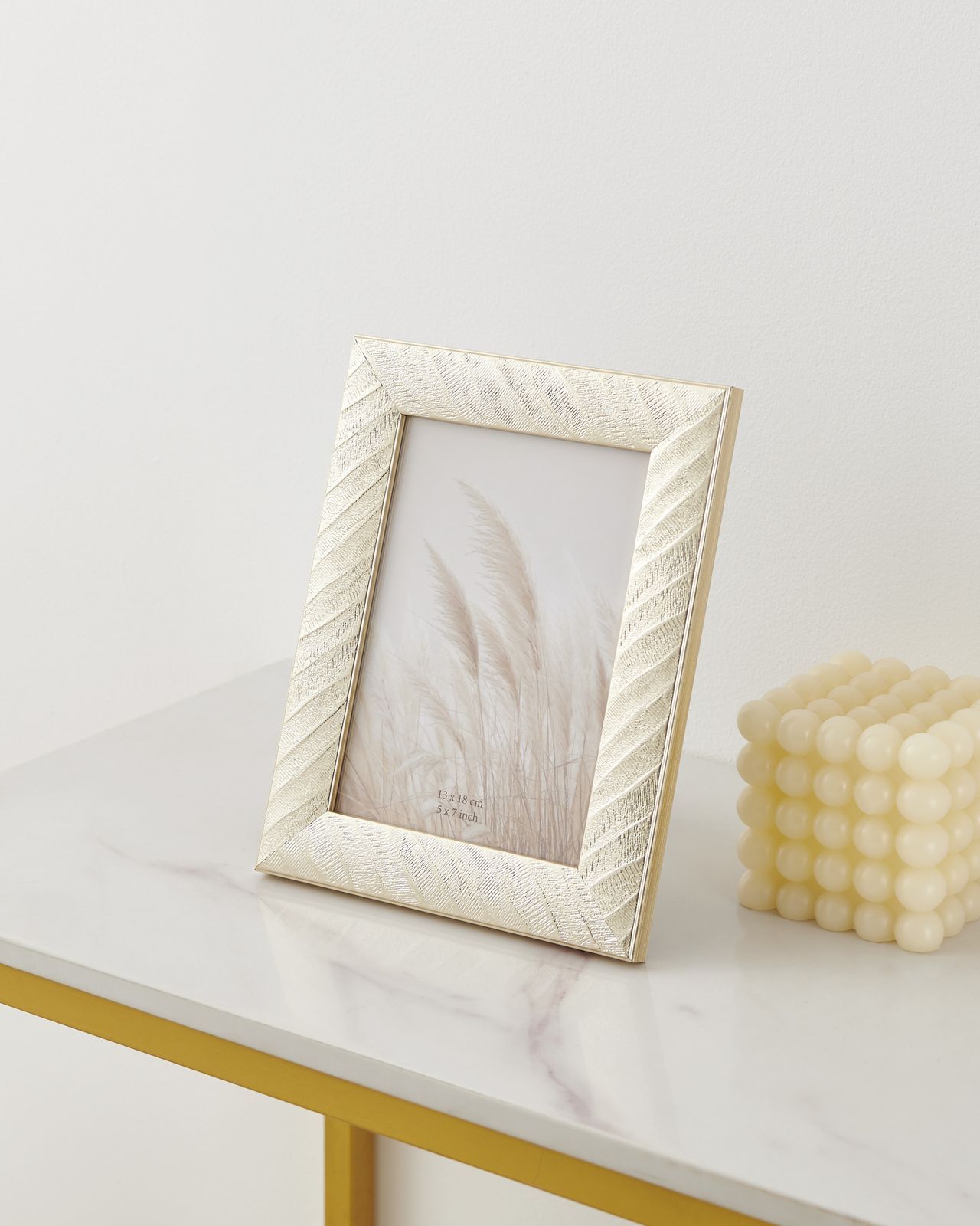 Decoratieve fotolijst met goudkleurige textuur en een beige inzetstuk met grasprint.