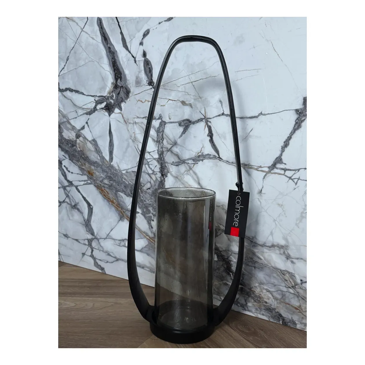 Zwarte lantaarn met handvat en cilindrische glazen kaarsenhouder.