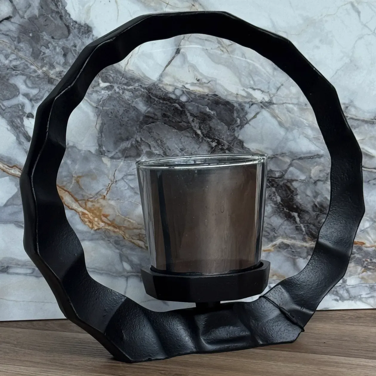 Zwarte metalen kaarsenhouder met een ronde rand en een glazen kaarsenhouder.