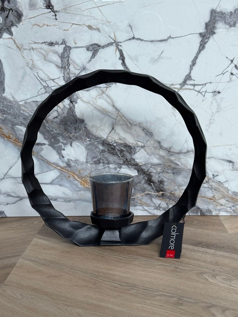 Zwarte ronde kaarsenhouder met een glazen votiefkaars in het midden.