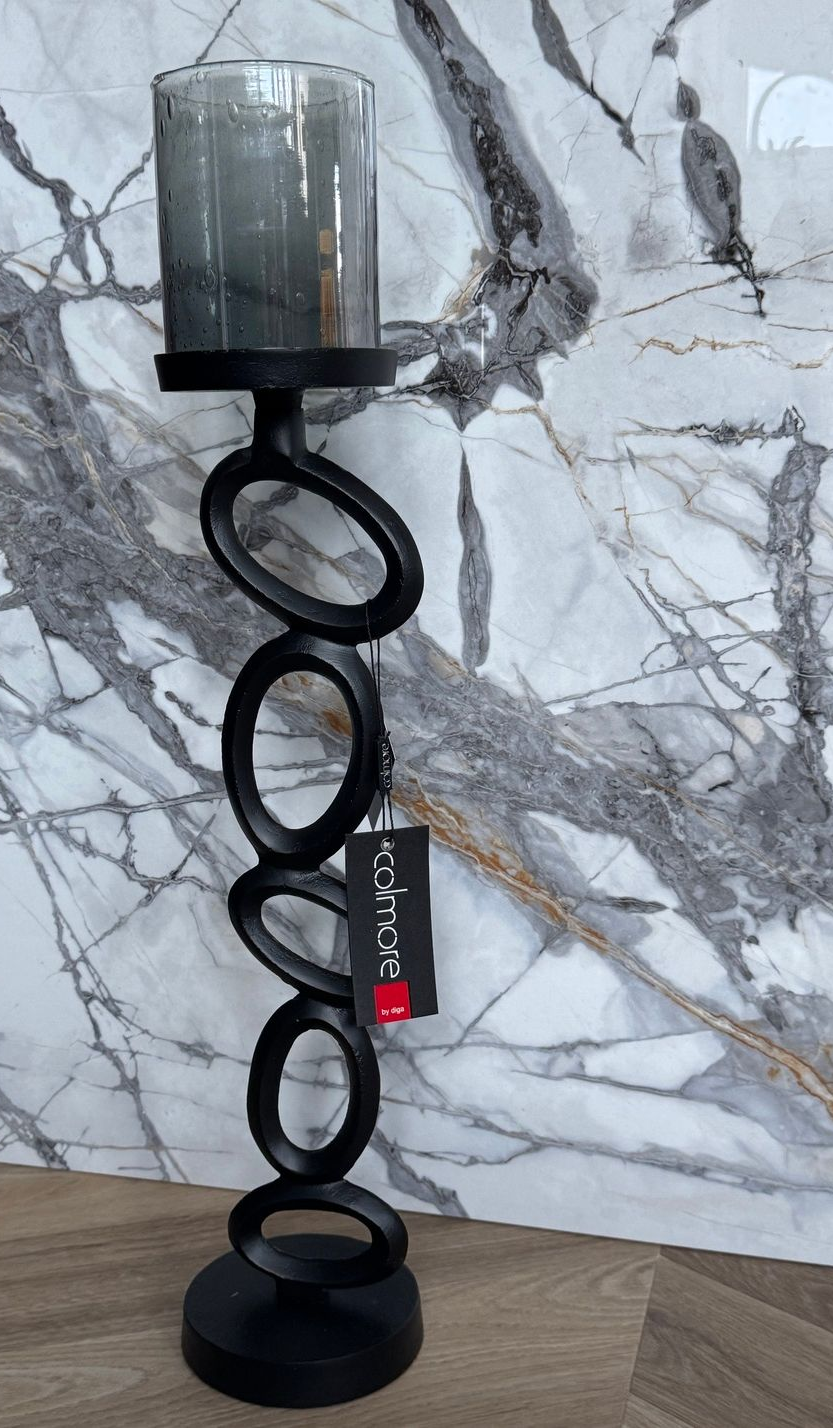 Zwarte metalen kaarsenhouder met trapsgewijs aflopende ovalen, afgewerkt met een glazen cilinder.