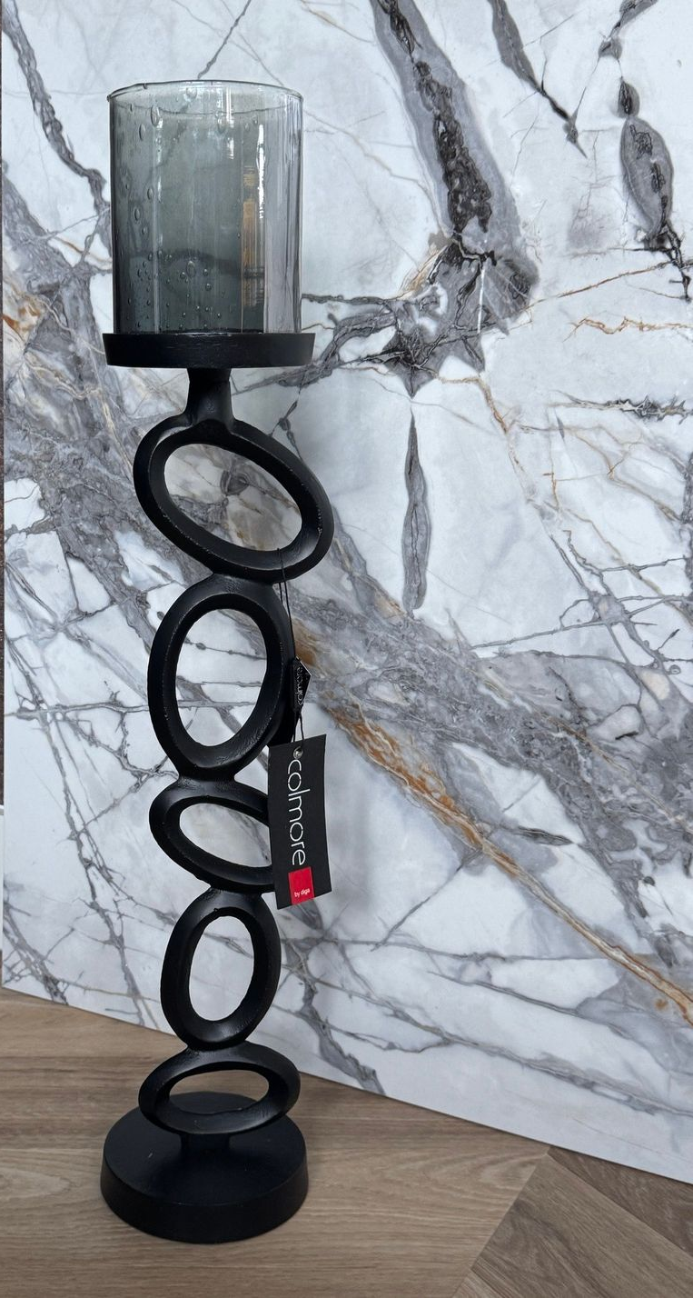 Zwarte metalen kaarsenhouder met trapsgewijs aflopende ovalen, afgewerkt met een glazen cilinder.